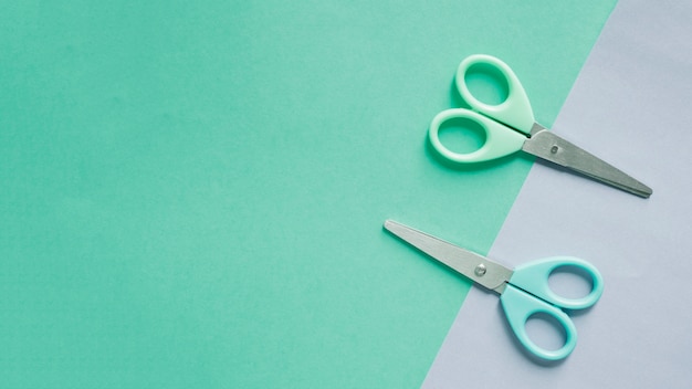 Free photo overhead view of two scissors on dual colorful background