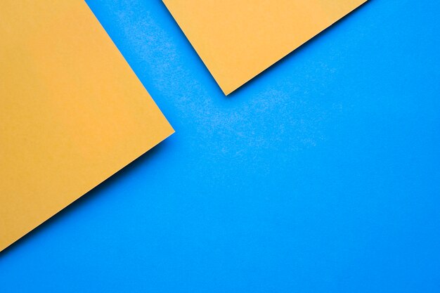 Overhead view of two yellow craftpapers on blue backdrop