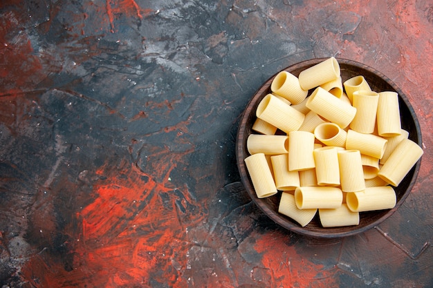 Free Photo overhead view of uncooked pastas inside the pot on the left side of black table