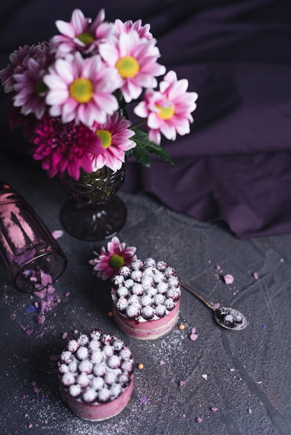 An overhead view of vase with tasty cheese blackcurrant cake on black textured backdrop