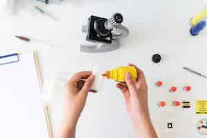 Free photo an overhead view of veterinarian pouring chemical on medical gauze in laboratory