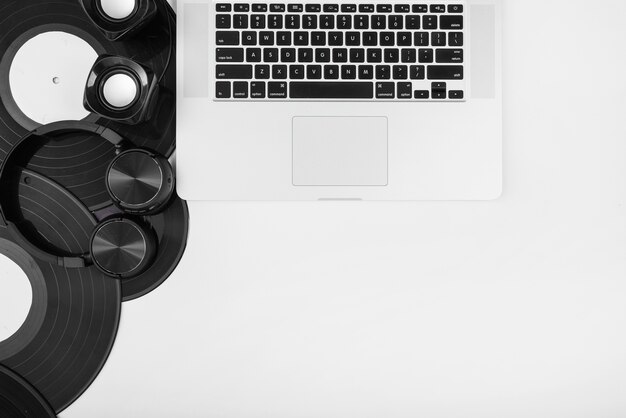 An overhead view of vinyl records; headphone and wireless speaker with laptop