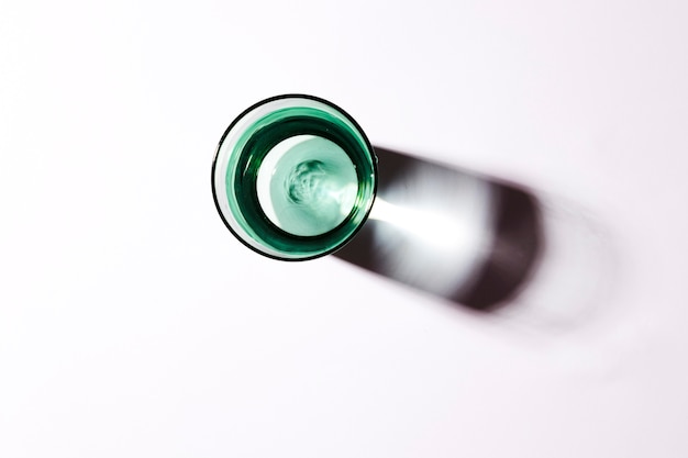 Free photo an overhead view of water in green glass on white backdrop