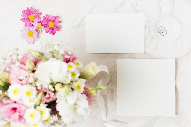 An overhead view of wedding bouquets with white card and rings on concrete backdrop