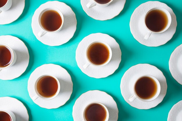 An overhead view of white ceramic cup and saucer on turquoise backdrop