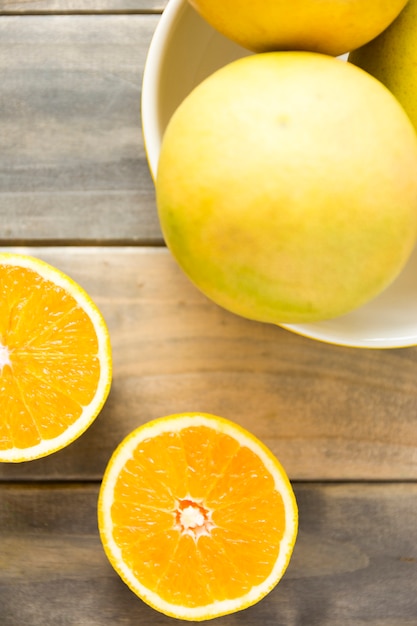 Free Photo an overhead view of whole and slices of orange on wooden table