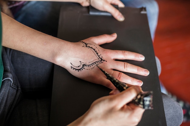 An overhead view of woman making heena tattoo from female artist