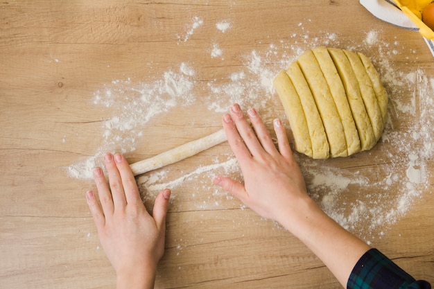 Free photo an overhead view of woman preparing homemade fresh italian pasta gnocchi on wooden table