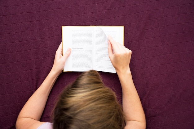 Free Photo an overhead view of woman reading book on bed