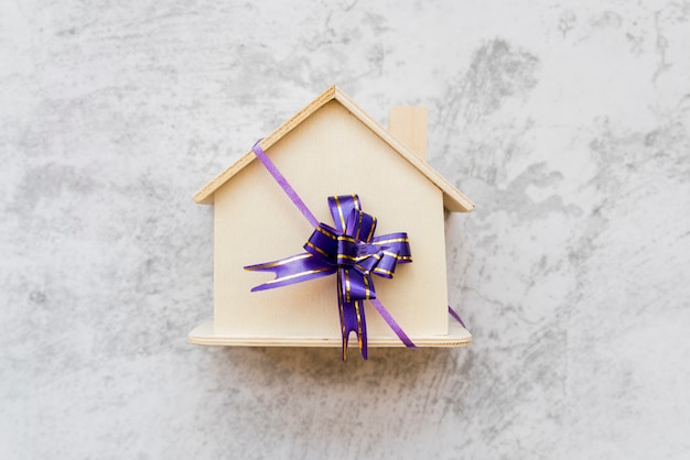 Free Photo an overhead view of wooden house tied with purple ribbon bow on concrete wall