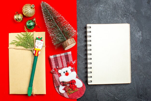 Overhead view of xsmas mood with christmas tree decoration acessories gift sock next to notebook on red and black backgroud