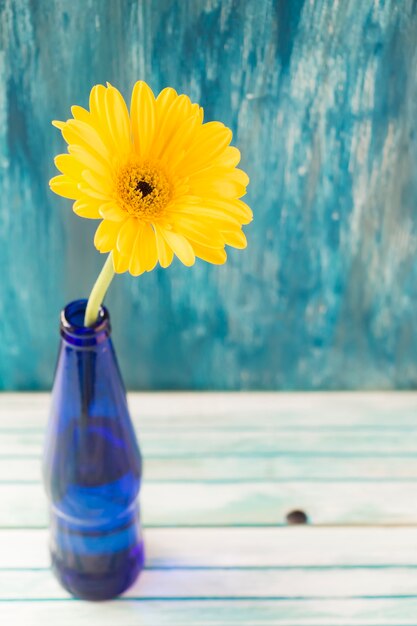 Free photo overhead view of yellow gerbera flower in the bottle on wooden table