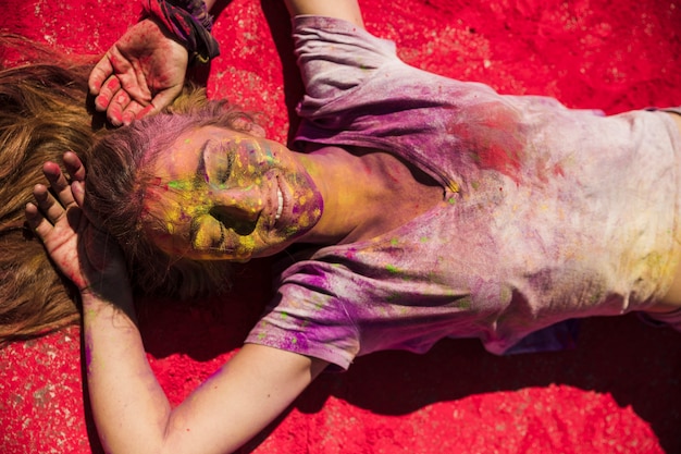 Free Photo an overhead view of young women lying on red holi powder