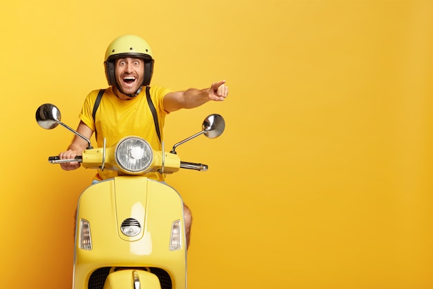 Overjoyed guy with helmet driving yellow scooter