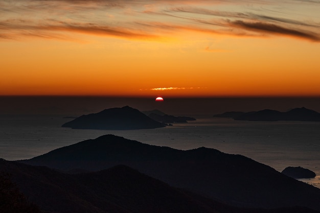 Free Photo overlooking view of a silhouette of mountains in the sea during sunset