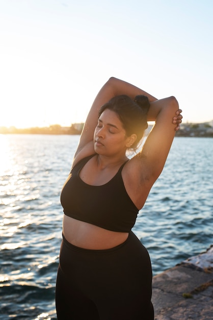 Free photo overweight woman exercising outdoors by the lake