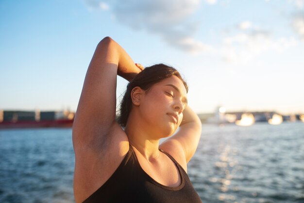 Overweight woman exercising outdoors by the lake