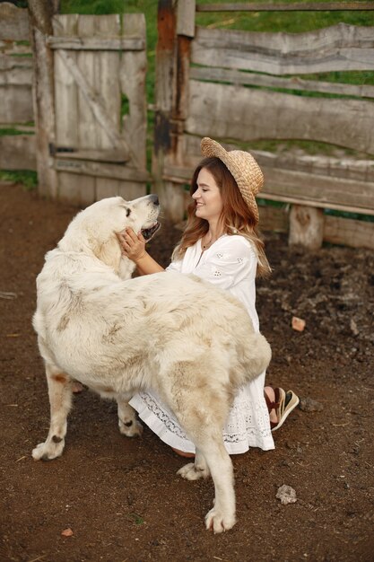 Owner and labrador retriever dog in a yard. Woman in a white dress. Golden retriever.