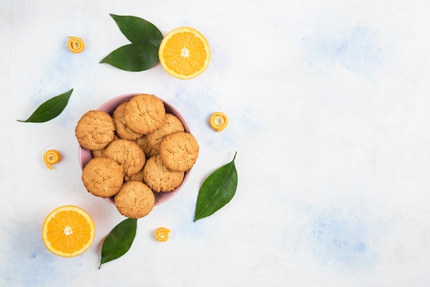 Free photo p view of homemade cookies on wooden board and fresh juicy oranges with leave over white background.