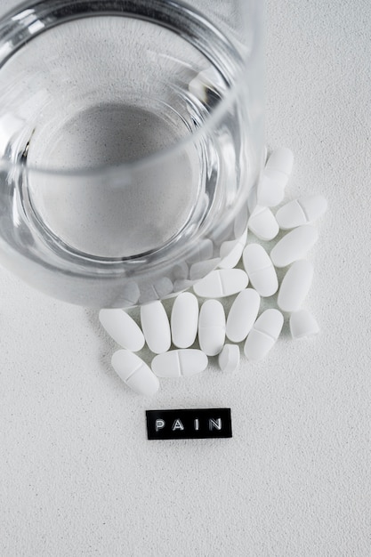 Free Photo painkiller white tablets near the glass of water on white backdrop