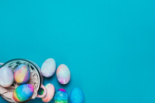 Painted easter eggs inside the cooking pot on the blue backdrop with copy space for writing the text