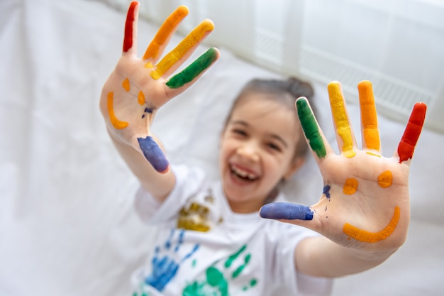 Painted smiles on the palms of a little girl. Funny bright drawings on children's palms.