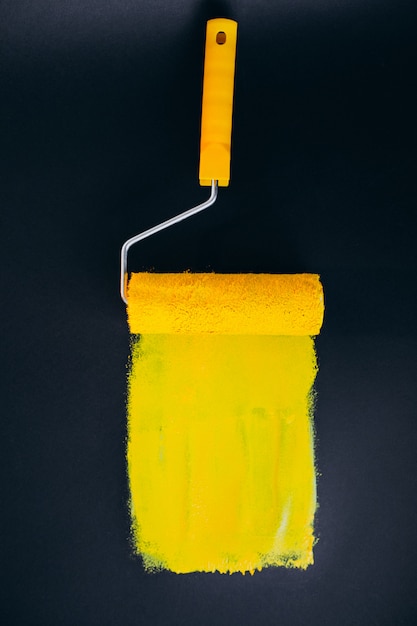 Free photo paintroller for repairs isolated on black background in yellow paints