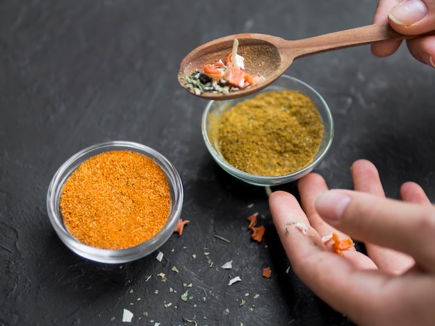 Free photo pair of bowls full of spices with hand holding spoon