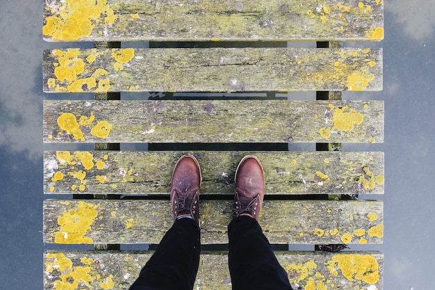 Free photo pair of brown leather shoes standing on an old grey and yellow bridge