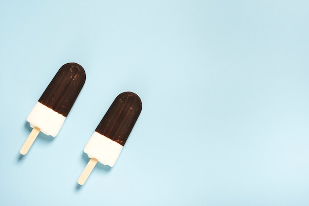 Free photo pair of ice cream half in chocolate on sticks