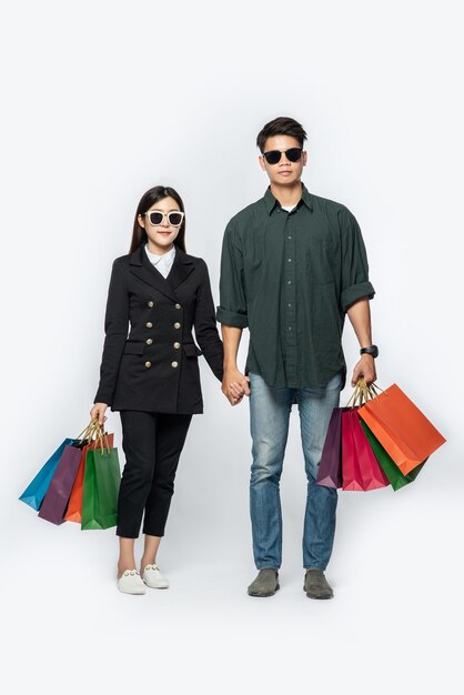 A pair of man and woman wearing glasses and carried lots of paper bags for shopping