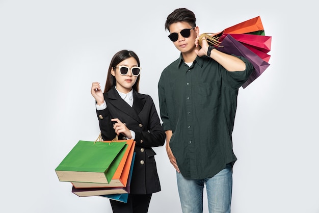 A pair of man and woman wearing glasses and carried lots of paper bags for shopping