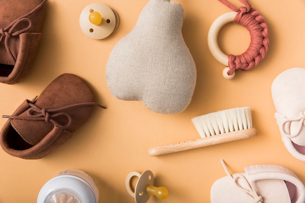 Pair of shoes; pacifier; stuffed pear; brush; milk bottle on an orange backdrop