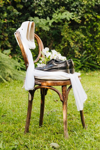 Pair of wedding high heels and shoes with scarf and flower bouquet on green grass in the park