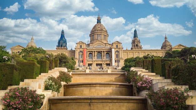 The Palau National in Barcelona, Spain gardens and people in front of it. Cloudy sky