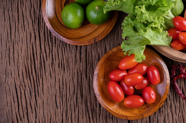 Palm sugar, red onions, dried peppers, tomatoes, cucumbers, yard long beans and lettuce in a bowl.