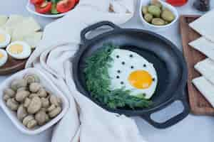 Free photo pan with omelet and boiled eggs, cheese, tomato, mushrooms on white.