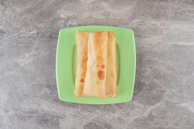 Pancakes stacked on a green platter on marble surface