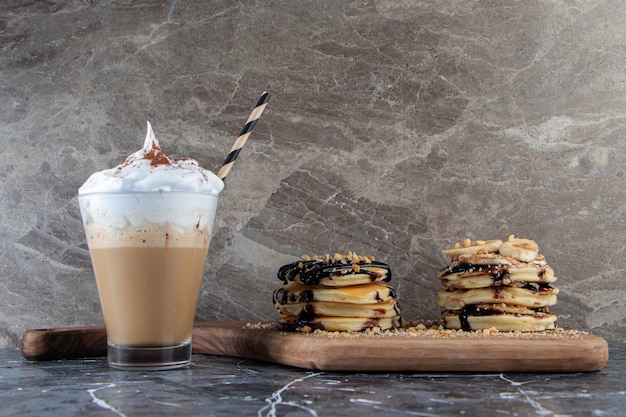 Free photo pancakes with banana and chocolate topping on wooden board with delicious coffee.