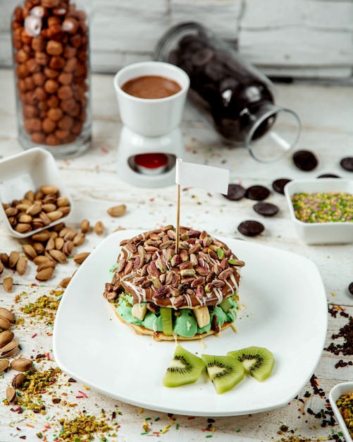 Free photo pancakes with banana and kiwi sprinkled with chocolate and pistachios