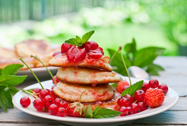 Free photo pancakes with berries on a wooden table in a summer garden