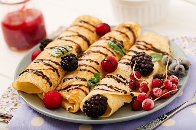 Free photo pancakes with chocolate, jam and berries. tasty breakfast.