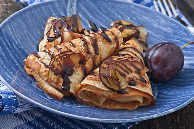 Pancakes with chocolate syrup and plums