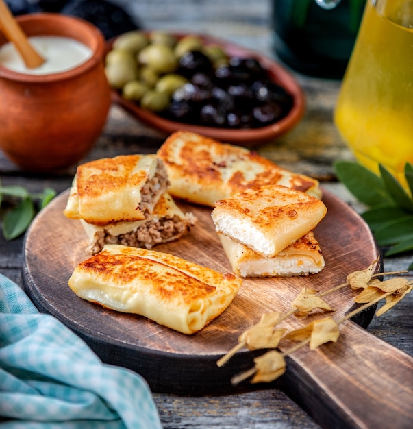 Free Photo pancakes with meat and cottage cheese on a wooden board