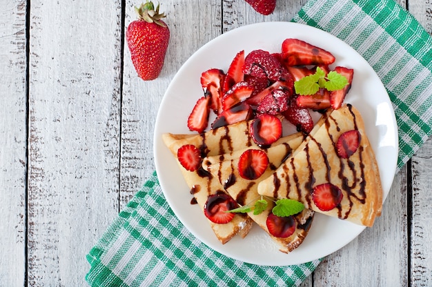 Pancakes with strawberries and chocolate decorated with mint leaf