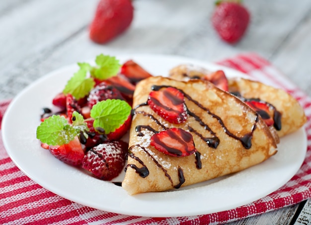 Pancakes with strawberries and chocolate decorated with mint leaf