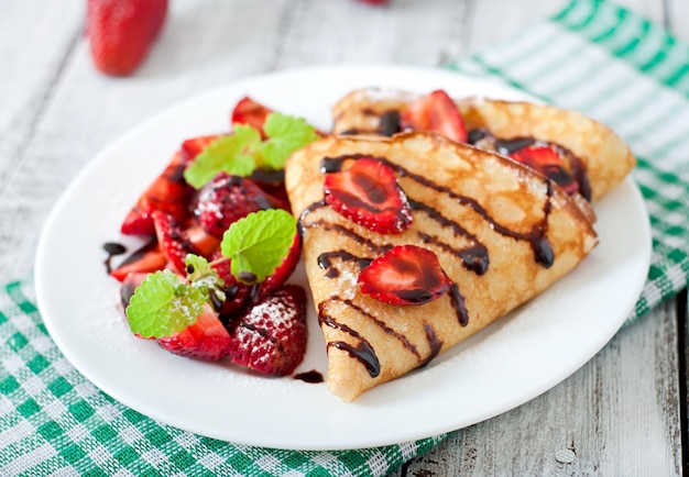 Pancakes with strawberries and chocolate decorated with mint leaf