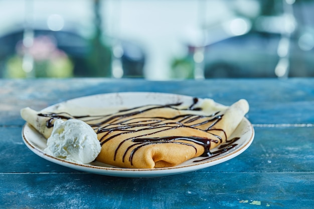 Free Photo pancakes with vanilla ice-cream, chocolate on the white plate in the blue surface 