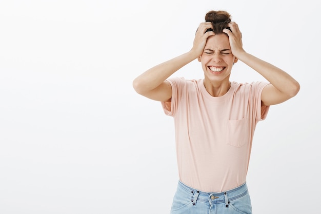 Free photo panicking young stylish woman posing against the white wall