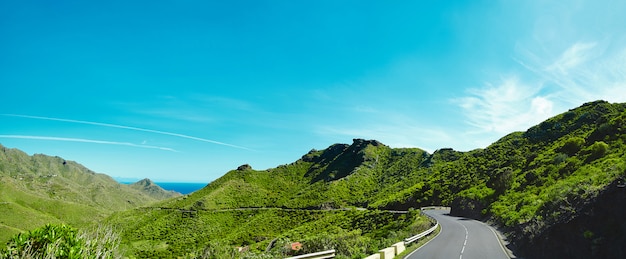 Panorama and beautiful view of mountains and blue sky with Asphalt road is meandering between blue fjord and moss mountains.